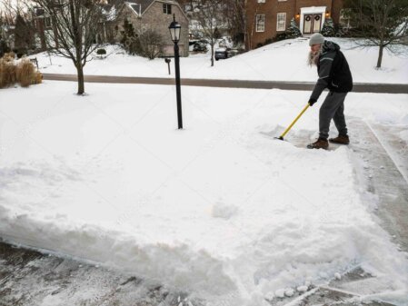 Schneeräumen auf Gehweg vor einem Haus